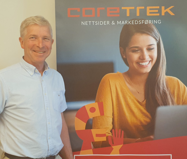 Rådgiver Jan Morten Andersen ved siden av et reklamebanner for CoreTrek